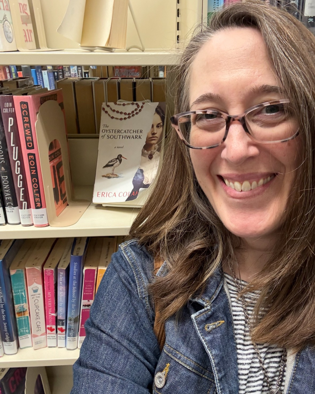 Erica Colahan-Ruggieri standing in a library next to her book The Oystercatcher of Southwark